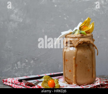 Chocolate Vegan breakfast smoothie with kiwi, coconut and physalis in the jar. Love for a healthy vegan food concept Stock Photo