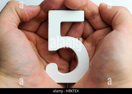 Hand holding number five on a white background. Stock Photo