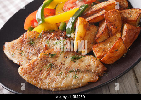 White fish fillet and potato wedges, fresh salad on a plate close-up. horizontal Stock Photo