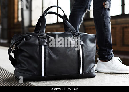 Male tourists are carrying luggage waiting train on the platform. Photo light and adjustable tone vintage.. Stock Photo