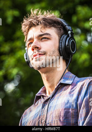 A young man listening to music on headphones. Stock Photo