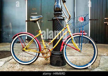 A bright and colorful vintage bicycle with a basket leaning against an old lamppost in the French Quarter of New Orleans Louisiana. Stock Photo