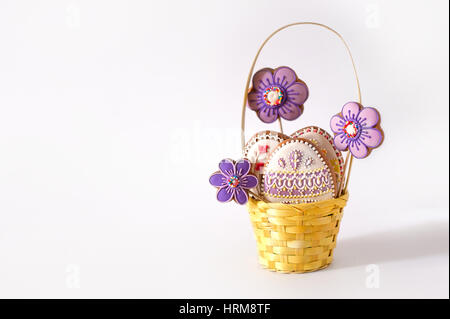 Little Easter is on a festive scarf. Multi-colored Easter eggs lie in a basket with decoration gingerbread Stock Photo