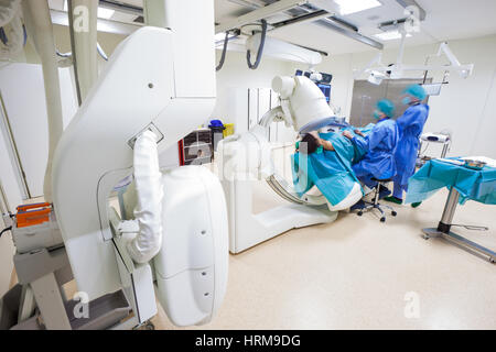 A laparoscopic surgery performed by two doctors, figures blurred, in a super hi-tech hospital operating room with scanner. Stock Photo