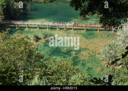 People walking at an elevated boardwalk and swimming at a lake at the Krka National Park in Croatia on a sunny day, viewed from above. Stock Photo