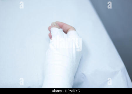 Doctor applying a plaster cast and bandages to patient forearm and wrist to immobilize after fracture injury. Stock Photo