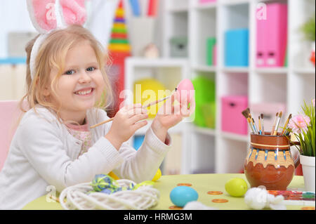 Happy girl with bunny ears getting ready for Easter and color eggs. Stock Photo