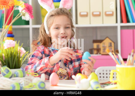 Happy girl with bunny ears getting ready for Easter and color eggs. Stock Photo