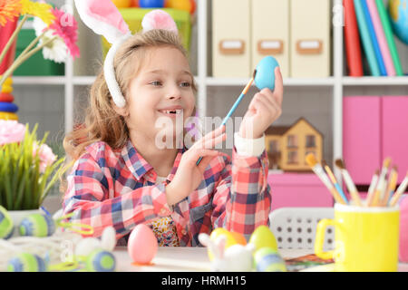 Happy girl with bunny ears getting ready for Easter and color eggs. Stock Photo