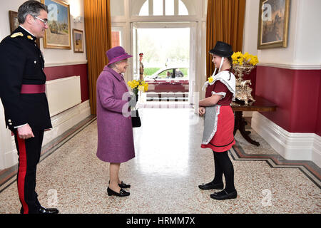 Ffion Williams, 10, presents a bunch of daffodils to Queen Elizabeth II at Lucknow Barracks in Tidworth, Wiltshire, as she departs following a visit to the Royal Welsh Regiment to mark St David's Day. Stock Photo
