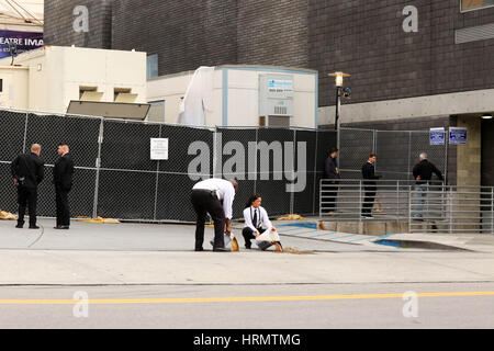 Hollywood, California, USA. 26th Feb, 2017. Oscar staff members dumping a black liquid into city drains, during the show. They would not tell press what the liquid was or whether it was toxic or polluting. No answers given on why they were doing this on North Orange Drive. During the Oscars ceremony, North Orange Drive was blocked from public automobile usage and used only by Oscar staff only. This back entrance to Dolby Theater and its' parking lot was a beehive of activity for Oscar staff. Credit: Katrina Kochneva/ZUMA Wire/Alamy Live News Stock Photo
