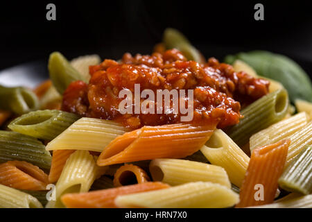 Colored penne pasta with ragu sauce or bolognese pasta on plate Stock Photo