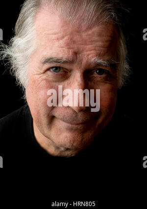 close up portrait head shot of a senior man in his 50's. male wearing black t-shirt and isolated on black background. Stock Photo