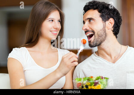 Couple eating salad on the sofa Stock Photo