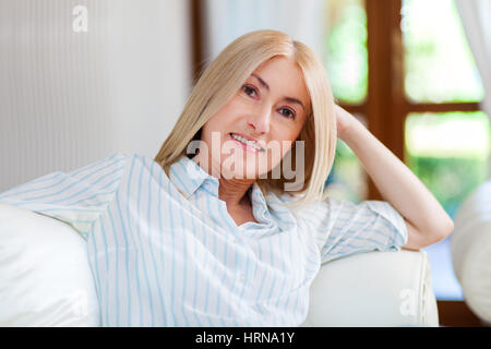 Portrait of a smiling woman relaxing on the couch in her home Stock Photo