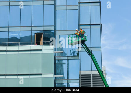 Men working on building exterior atop a boom lift - USA Stock Photo