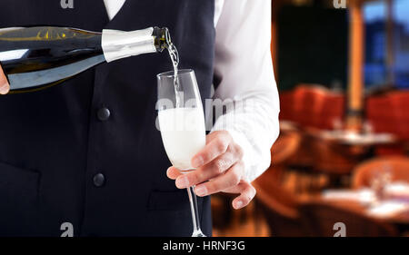Portrait of a waiter pouring champagne into a flute Stock Photo