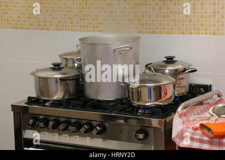 many large steel pots and small saucepan on the stove inside the restaurant during the preparation of food Stock Photo