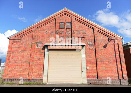 facade of old red brick warehouse with shutter door or rolling door Stock Photo
