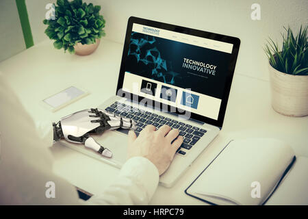 man working with laptop using robotic hand. Innovative website on screen Stock Photo