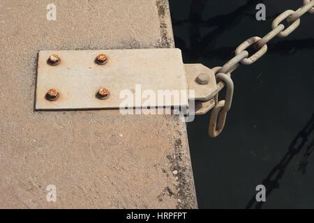 Steel mooring point on quayside with chain attached Stock Photo