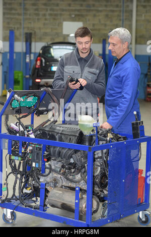 apprentice mechanic working on engine block with senior teacher Stock Photo