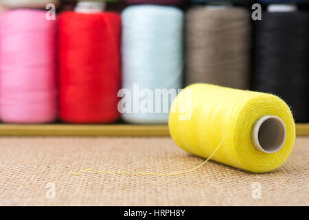 Yellow spools of thread on sackcloth table Stock Photo