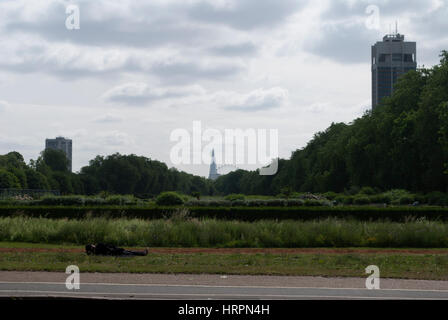 Homeless man sleeping on grass at the edge of Hyde Park with The Shard in the distance Stock Photo