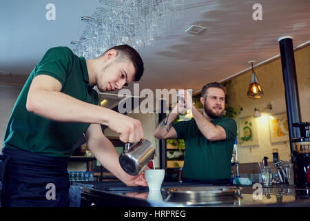 Two bartender barista working behind the bar in the workplace. Stock Photo