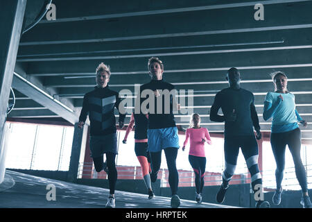 Young athletes in sportswear running at stadium against windows. Stock Photo