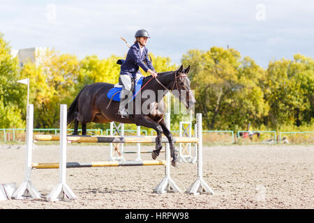 Young horseback sportswoman jumping over obstacles on show jumping competition Stock Photo