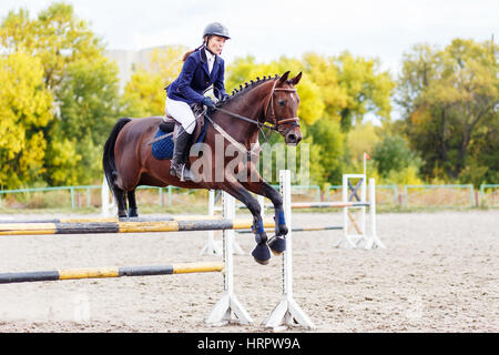 Young horseback sportswoman jumping over obstacles on show jumping competition Stock Photo