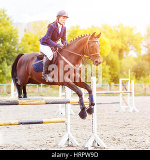 Young horseback sportswoman jumping over obstacles on show jumping competition Stock Photo