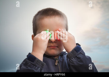 Kid playing with colored ping pong ball making faces Stock Photo