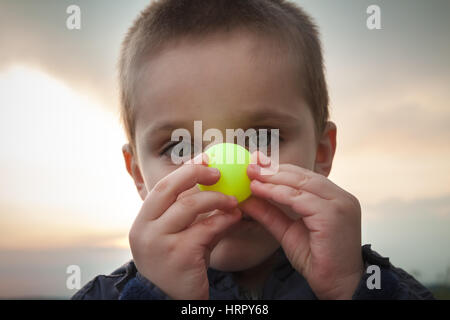 Kid playing with colored ping pong ball making faces Stock Photo