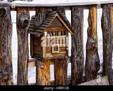 A wooden mailbox on a fence, looks like a house. Stock Photo