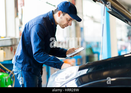 Mechanic using a tablet in his garage Stock Photo
