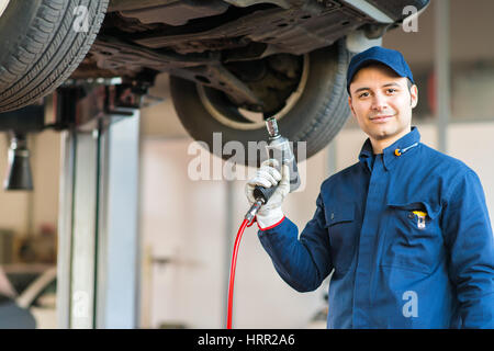 Portrait of a mechanic replacing a wheel Stock Photo