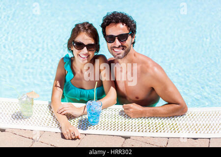 Happy couple having cocktails in the pool Stock Photo