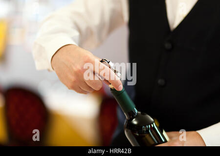 Waiter uncorking a wine bottle in a restaurant Stock Photo