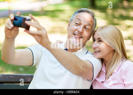 Portrait of a mature couple taking a self portrait in a park Stock Photo