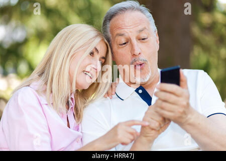 Portrait of a mature couple taking a self portrait in a park Stock Photo