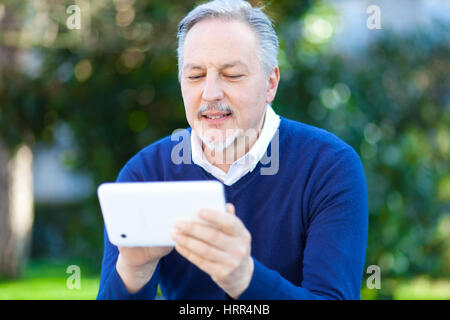 Senior man using a digital tablet outdoor in the park Stock Photo