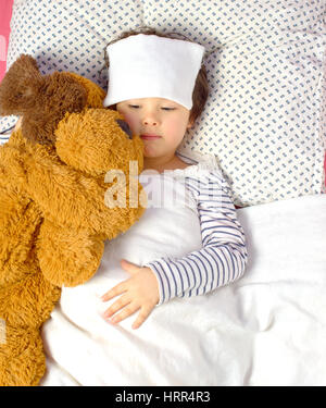 little girl with a headache in bed with teddy bear Stock Photo