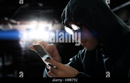 Hacker touching a smart phone screen Stock Photo