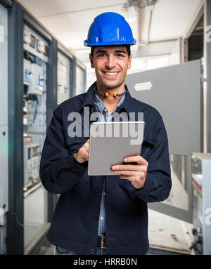 Electrician using a tablet in a cabinet Stock Photo