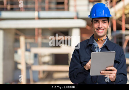 Worker using a tablet in front of a construction site Stock Photo