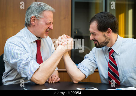 Business people doing arm wresling in their office. Shallow depth of field, focus on the man on the right Stock Photo