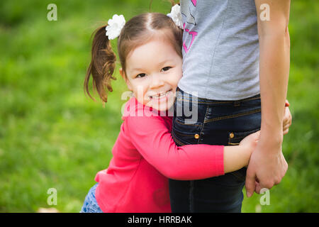 Closeup portrait of happy family. Little funny girl of 4 years age playing outside with her mum in spring city park. Horizontal color photography Stock Photo