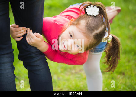 Closeup portrait of happy family over green grass background. Little funny girl of 4 years age playing outside with her parents in spring city park. H Stock Photo